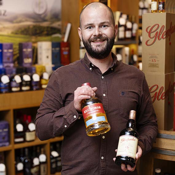 Ekspedient med diverse whisky i hånden i H.J. Hansen Vin butikken